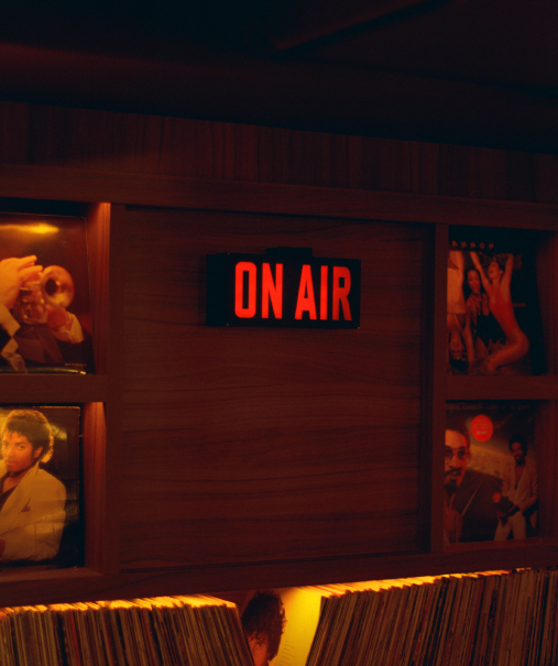 Panneau ON AIR lumineux rouge entre pochettes de disques vinyle dans la cabine DJ – Cat Club Courchevel