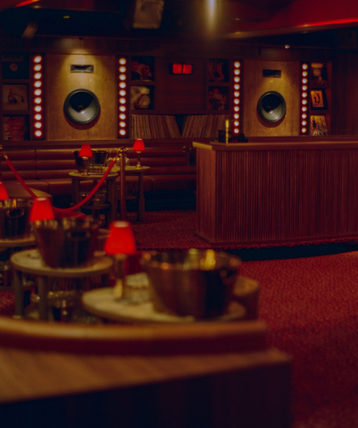 Salle du Cat Club Courchevel avec enceintes illuminées, panneau ON AIR, cabine DJ et table service en premier plan – lounge club courchevel