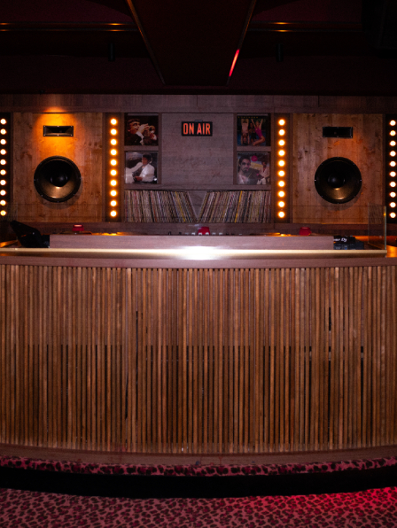 Cabine DJ frontale du Cat Club Courchevel avec platines Pioneer, panneau ON AIR, enceintes et moquette l&eacute;opard rose &ndash; club courchevel