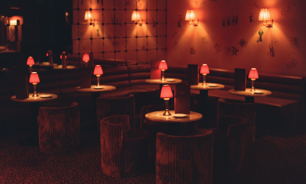 Salle du Cat Club Courchevel avec tables rondes, chauffeuses cannel&eacute;es, lampes rouges et mur capitonn&eacute; illustr&eacute; &ndash; bar lounge courchevel