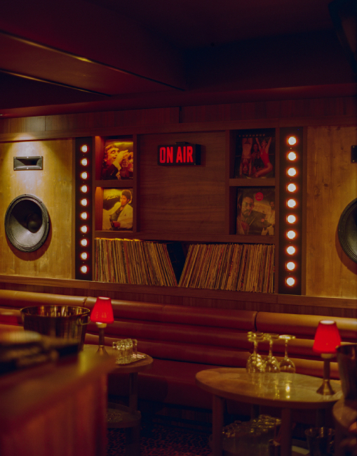Salle du Cat Club avec enceintes, collection de vinyles, panneau ON AIR illuminé et banquettes cuir – club courchevel
