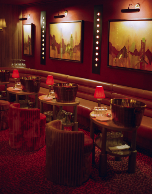 Salle lounge du Cat Club avec tableaux éclairés, banquette cuir, tables rondes et seaux à champagne – privatisation courchevel